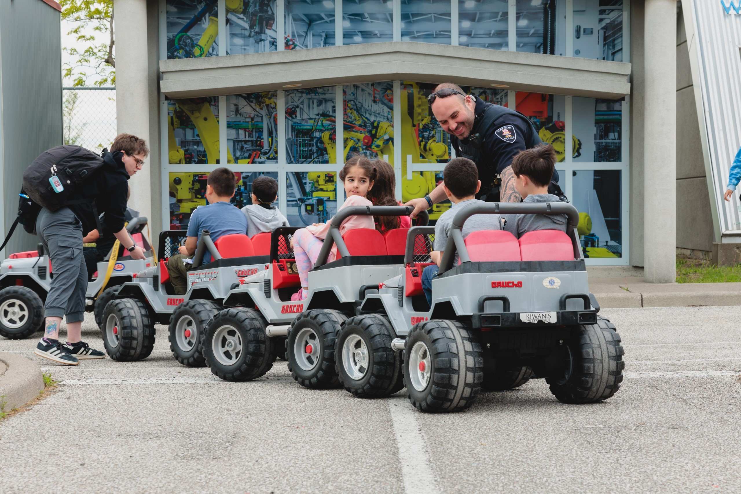 Children riding toy jeeps with a police officer